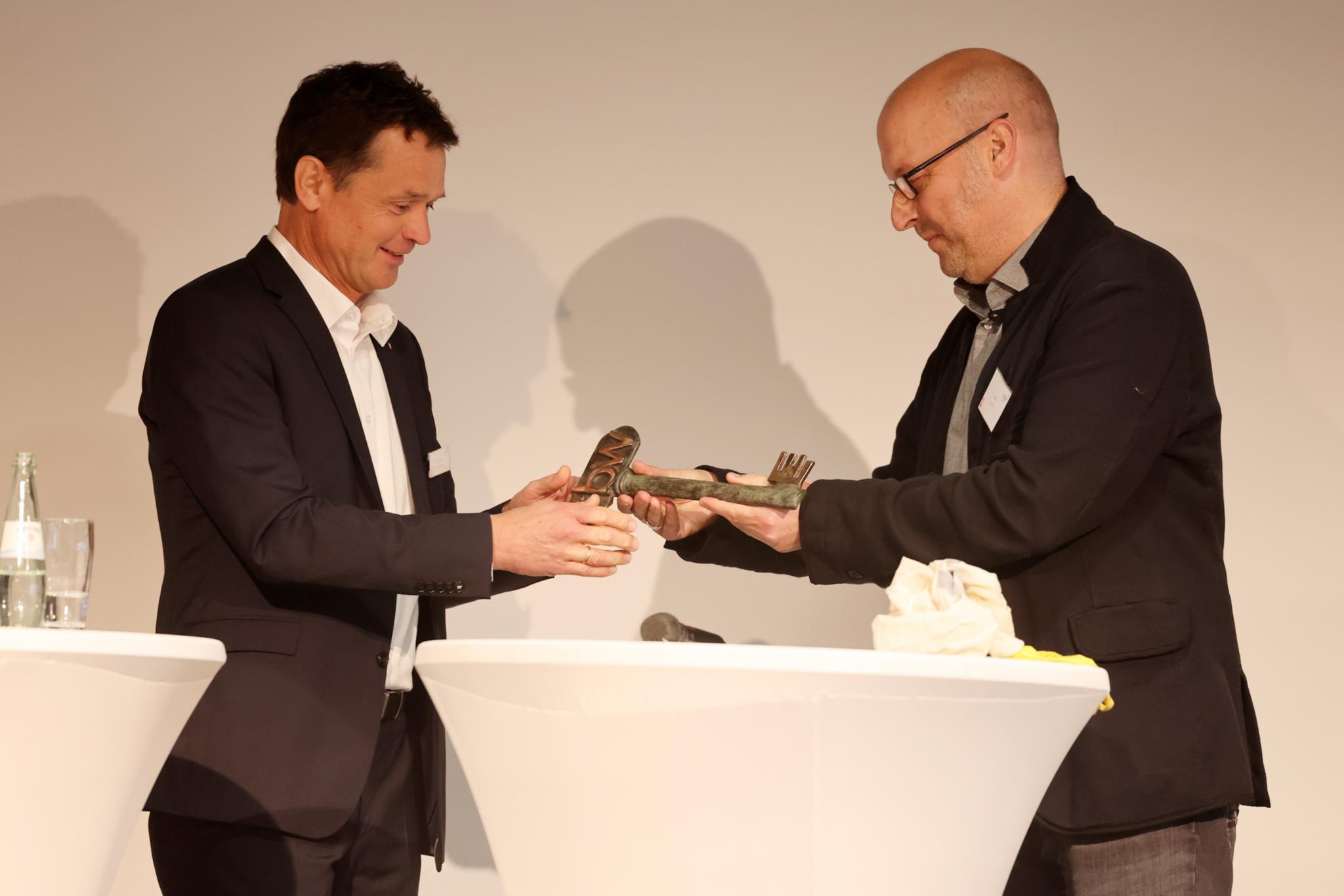 Geschäftsführer Michael Doersch nimmt von Architekt Oliver Blum einen symbolischen Schlüssel entgegen