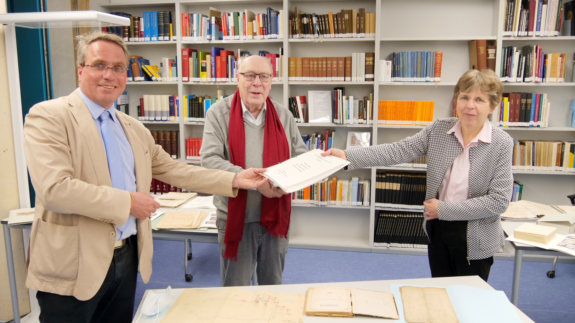 Übergabe im Diözesanarchiv: Dr. Peter Nieveler (M.) und Pfarrer Josef Wolff (l.) nehmen das Findbuch von Dr. Beate Sophie Fleck, Leiterin des Diözesanarchivs Aachen, entgegen. (c) Bistum Aachen - Anja Klingbeil