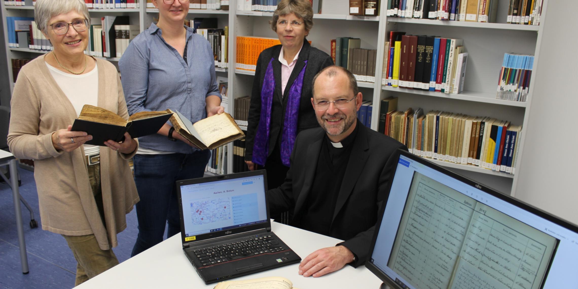 Mit 80.000 digitalisierten Seiten aus Kirchenbüchern startet das Bistum Aachen auf der Online-Plattform 'Matricula': Die Archivarinnen Marita Hermanns-Kuck (v.l.) und Charlotte Treutler drückten gemeinsam mit Dr. Beate Fleck, Leiterin des Diözesanarchivs, und Generalvikar Dr. Andreas Frick symbolisch den Startknopf.