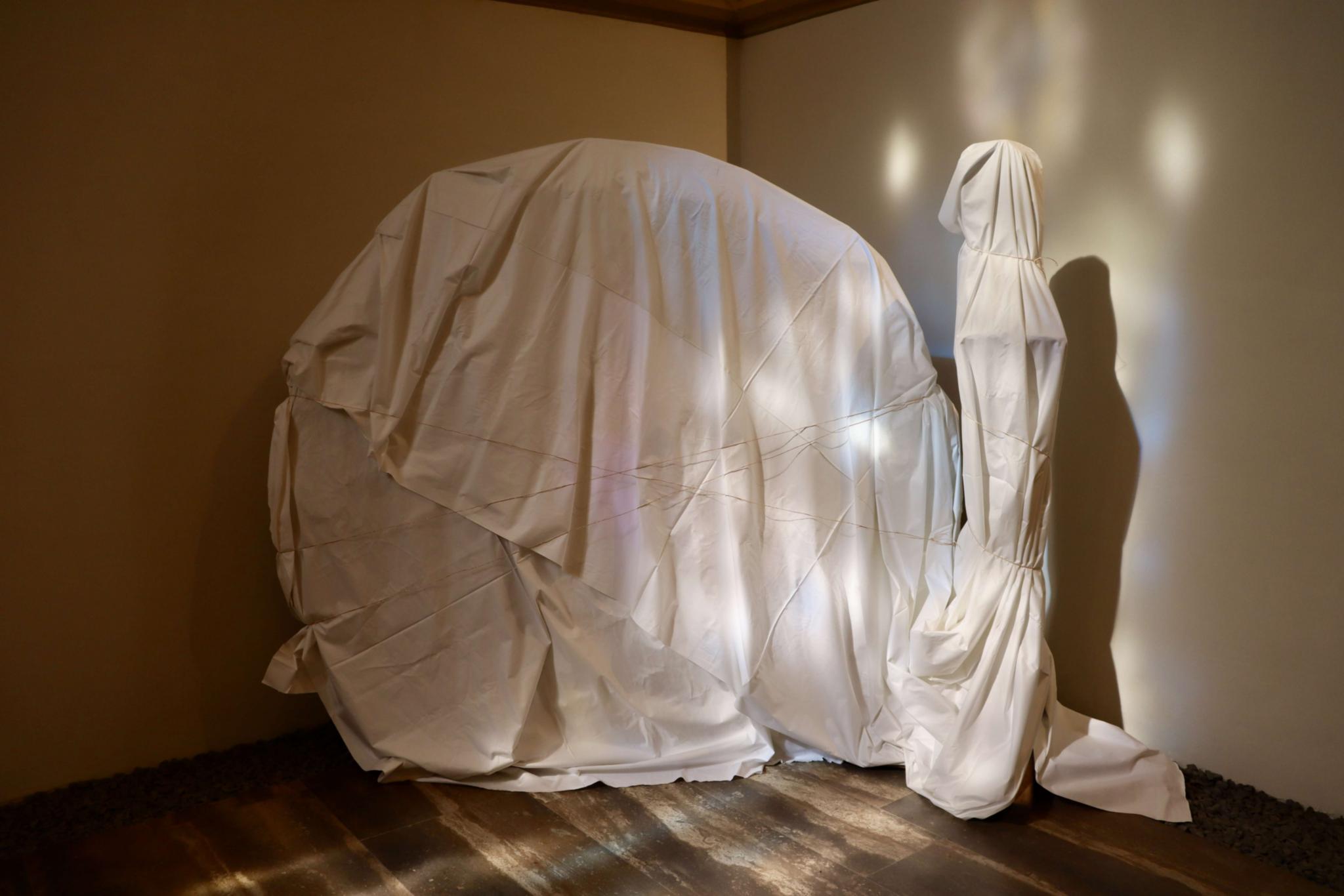 Eine Skulptur, die von einem Tuch verhüllt wird.