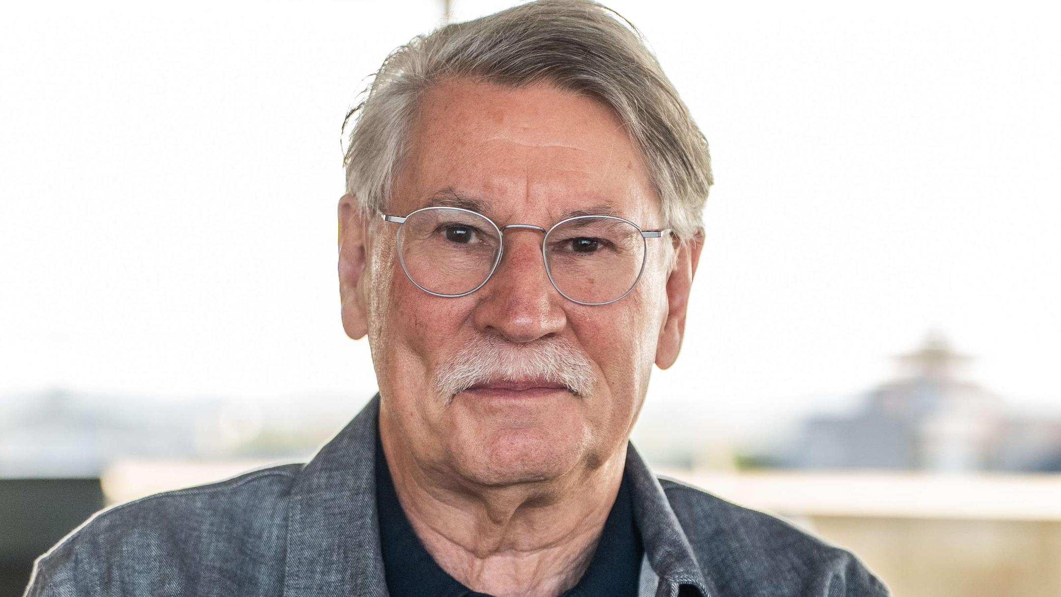 Mann mit Brille, mit weißem Oberlippenbart, Jeanshemd und schwarzem T-Shirt