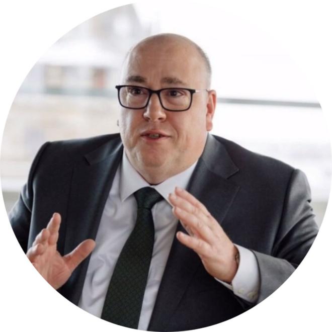 Mann mit Glatze und schwarzer Bille, gestikulierend, konzentrierter Blick