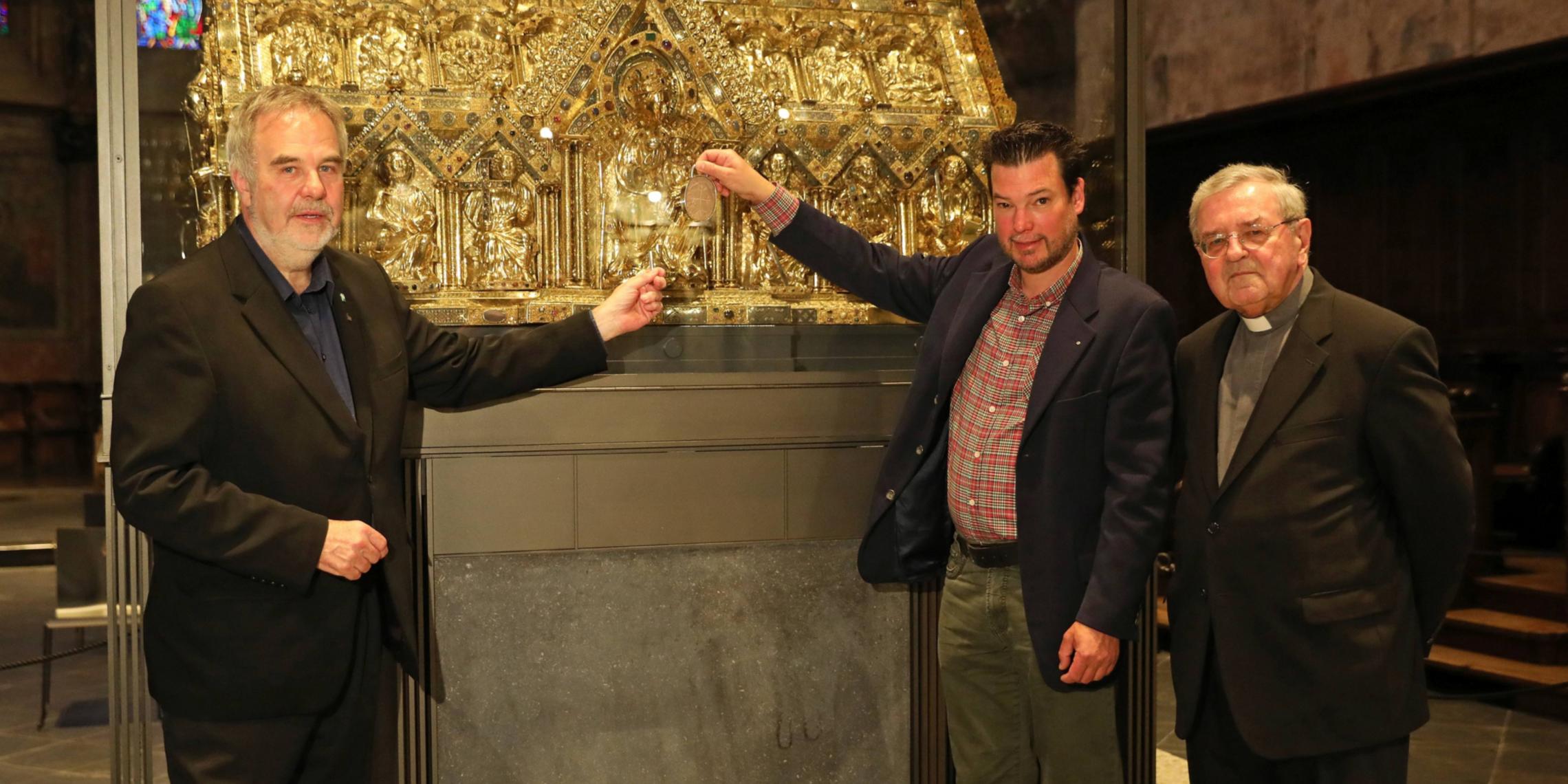 Dompropst Rolf-Peter Cremer (v.l.), Goldschmied Thomas Zintzen und Stifter Bischof em. Dr. Heinrich Mussinghoff vor Marienschrein im Aachener Dom.