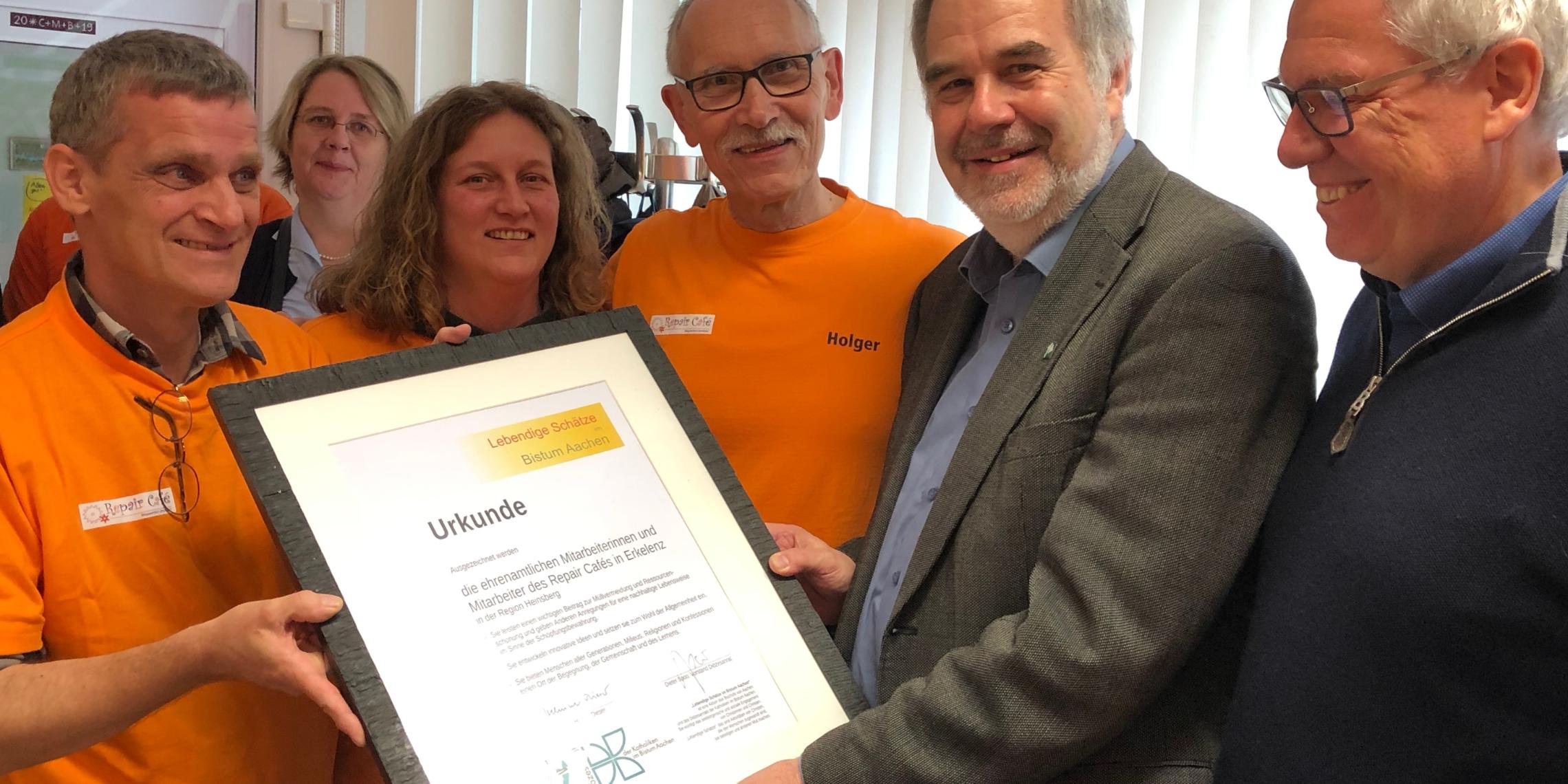 Pfarrer Rolf-Peter Cremer (2.v.r), Leiter der Hauptabteilung Pastoral / Schule / Bildung, und Dieter Spoo (r.), Diözesanrat der Katholiken, übergaben die Urkunde an die Ehrenamtlichen des Repair Cafés.