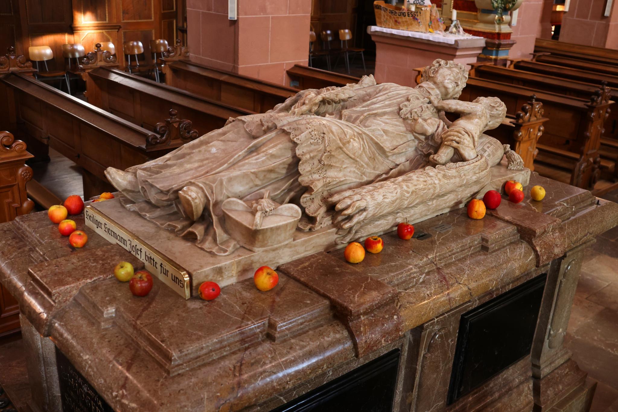 Grabmal des Hl. Hermann Josef im Kloster Steinfeld. Auf der Grabplatte liegen Äpfel.
