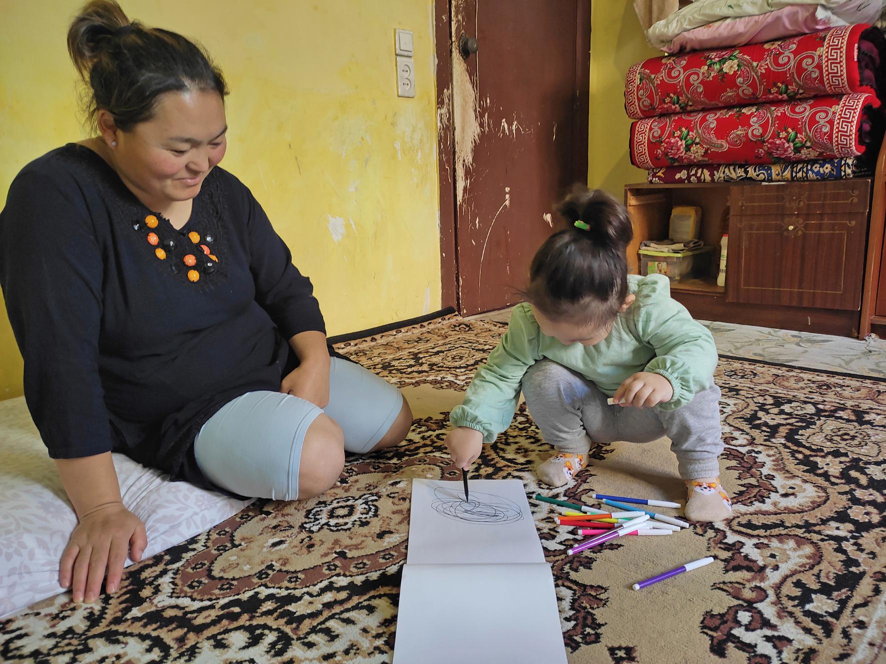 Perizad und ihre Tochter Aziza. Außer den Teppichen, auf denen sie schlafen und sitzen, besitzt die dreiköpfige Familie kein einziges Möbelstück. (c) SPSF