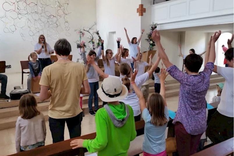 Familien singen mit einer Musikgruppe in einem Gottesdienstraum