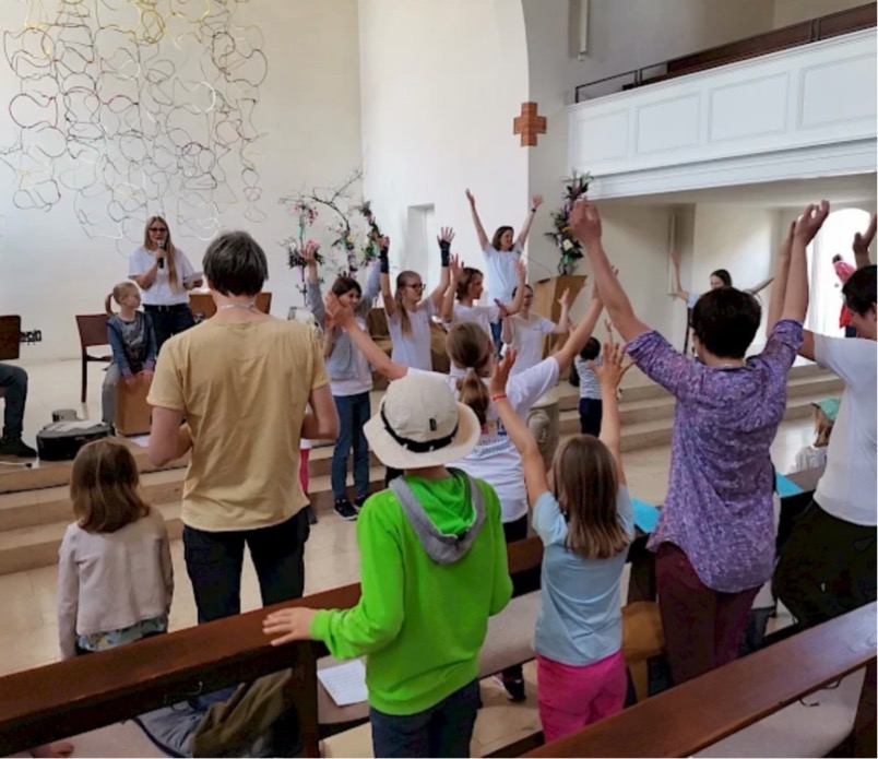 Familien singen mit einer Musikgruppe in einem Gottesdienstraum