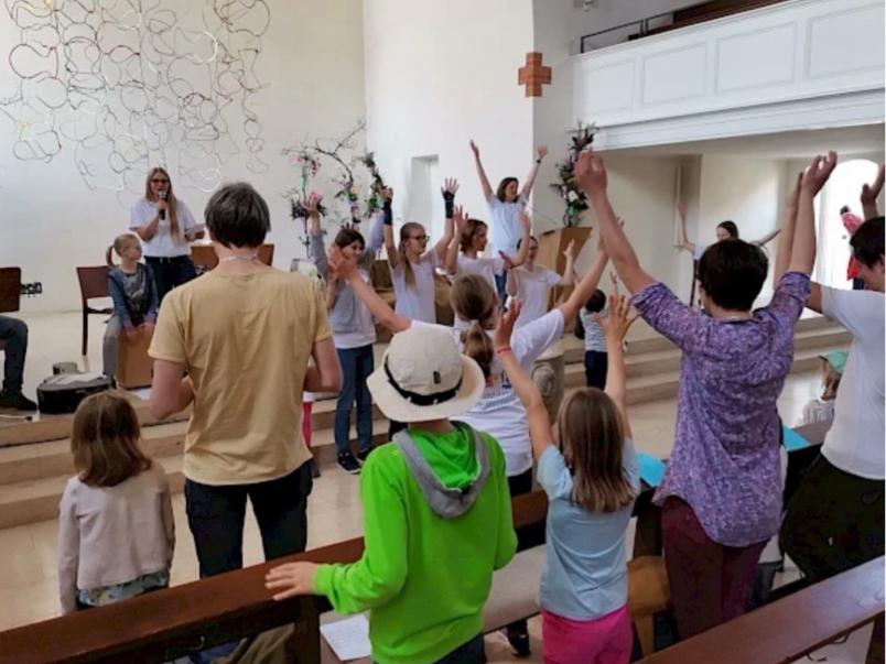 Familien singen mit einer Musikgruppe in einem Gottesdienstraum