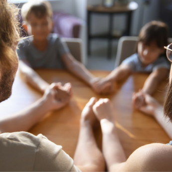 Familie sitzt am Tisch und betet