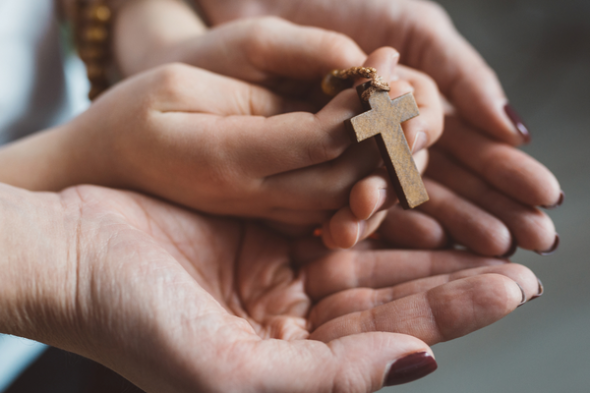 Erwachsenen Hände und Kinderhände halten ein Kreuz