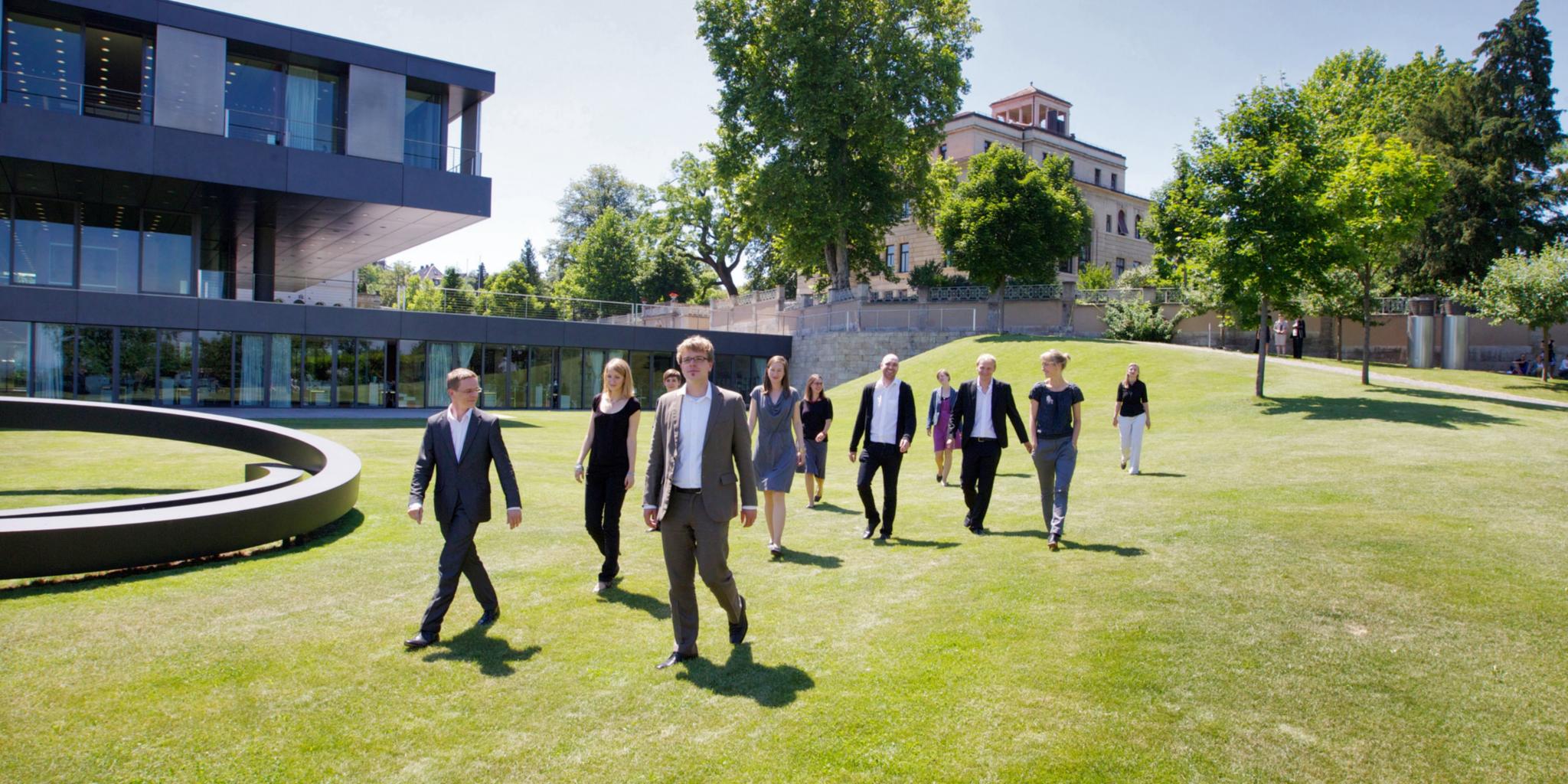 eine Gruppe junger Menschen geht über eine Wiese, alle haben das gleiche Ziel - gehen in die gleiche Richtung