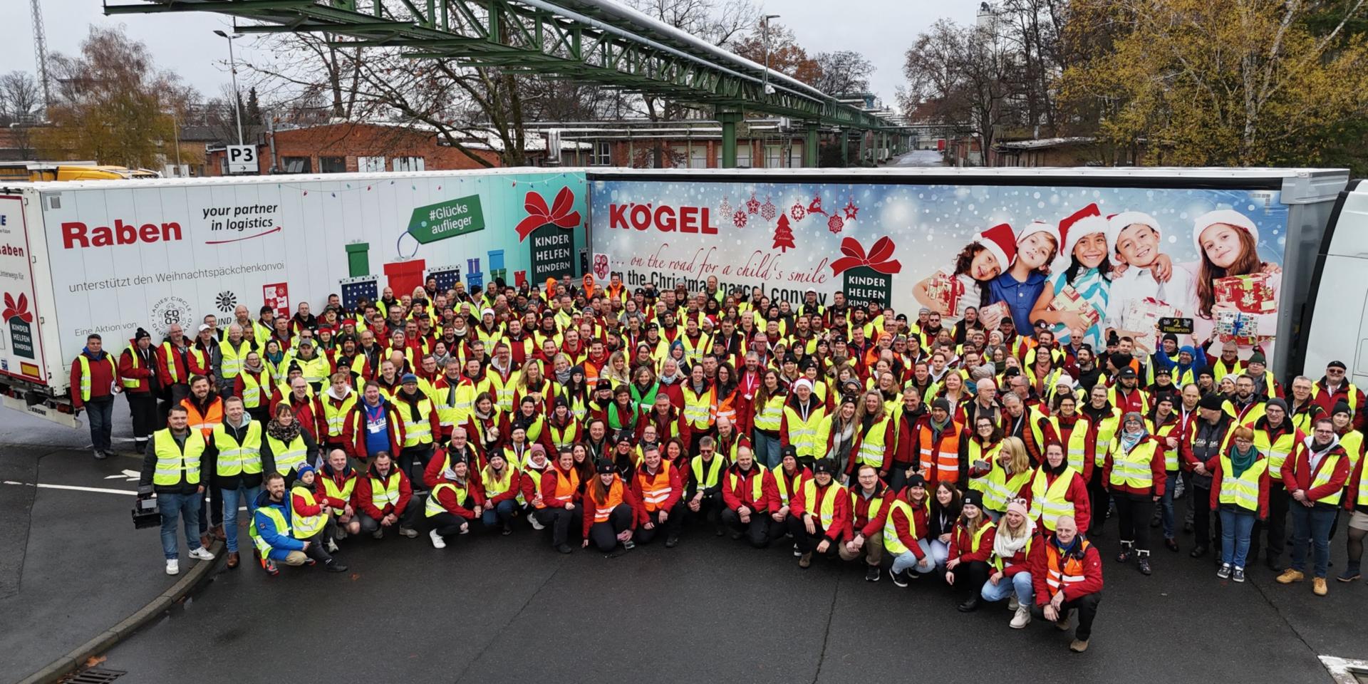 viele ehrenamtlich Helfende stehen vor den mit Geschenken beladenen LKWs