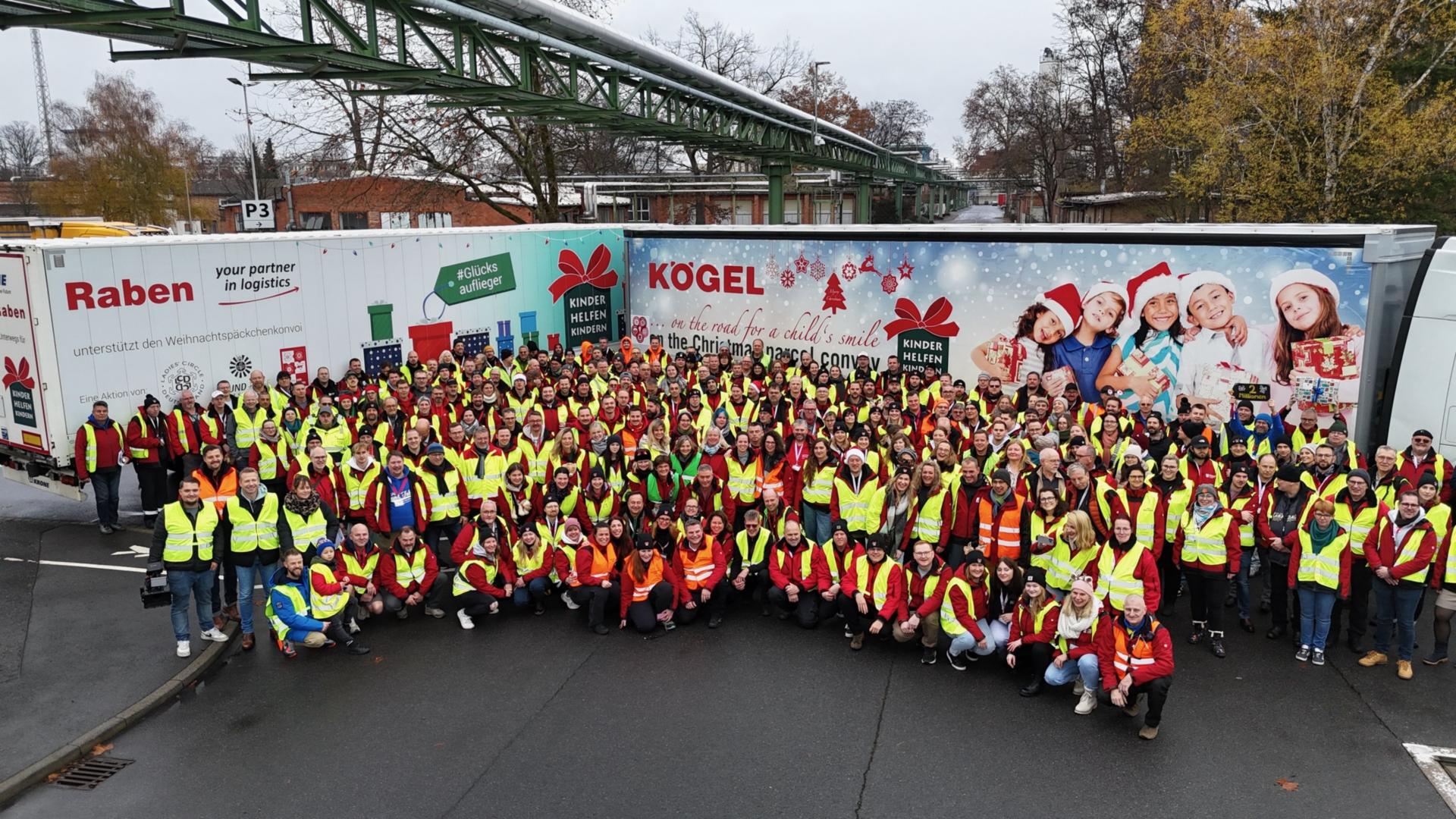 Der Weihnachtspäckchenkonvoi geht bald wieder auf Tour viele ehrenamtlich Helfende stehen vor den mit Geschenken beladenen LKWs