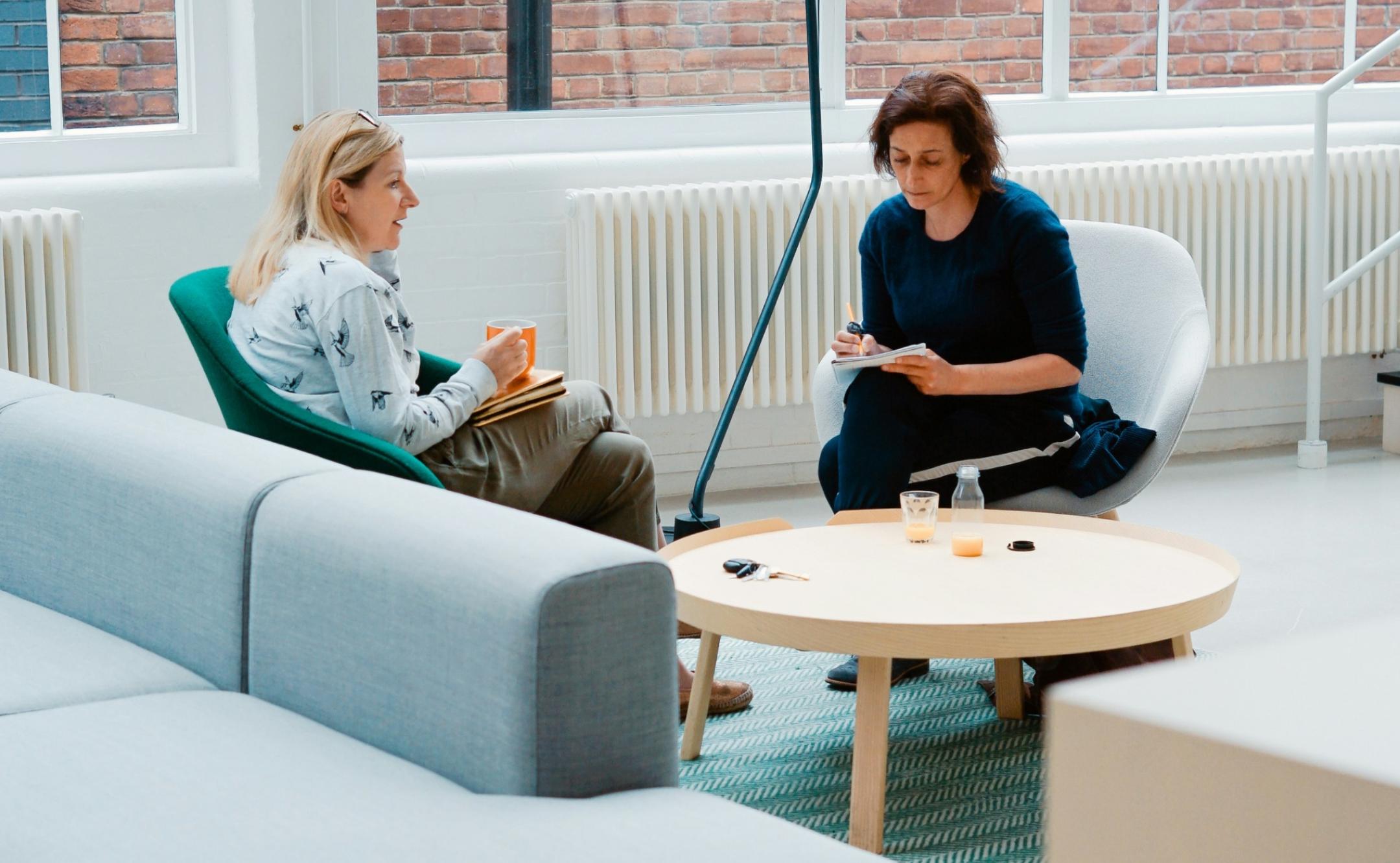 Dialogsituation zwischen zwei Frauen in einem großen Büro, Beratung, Schulung
