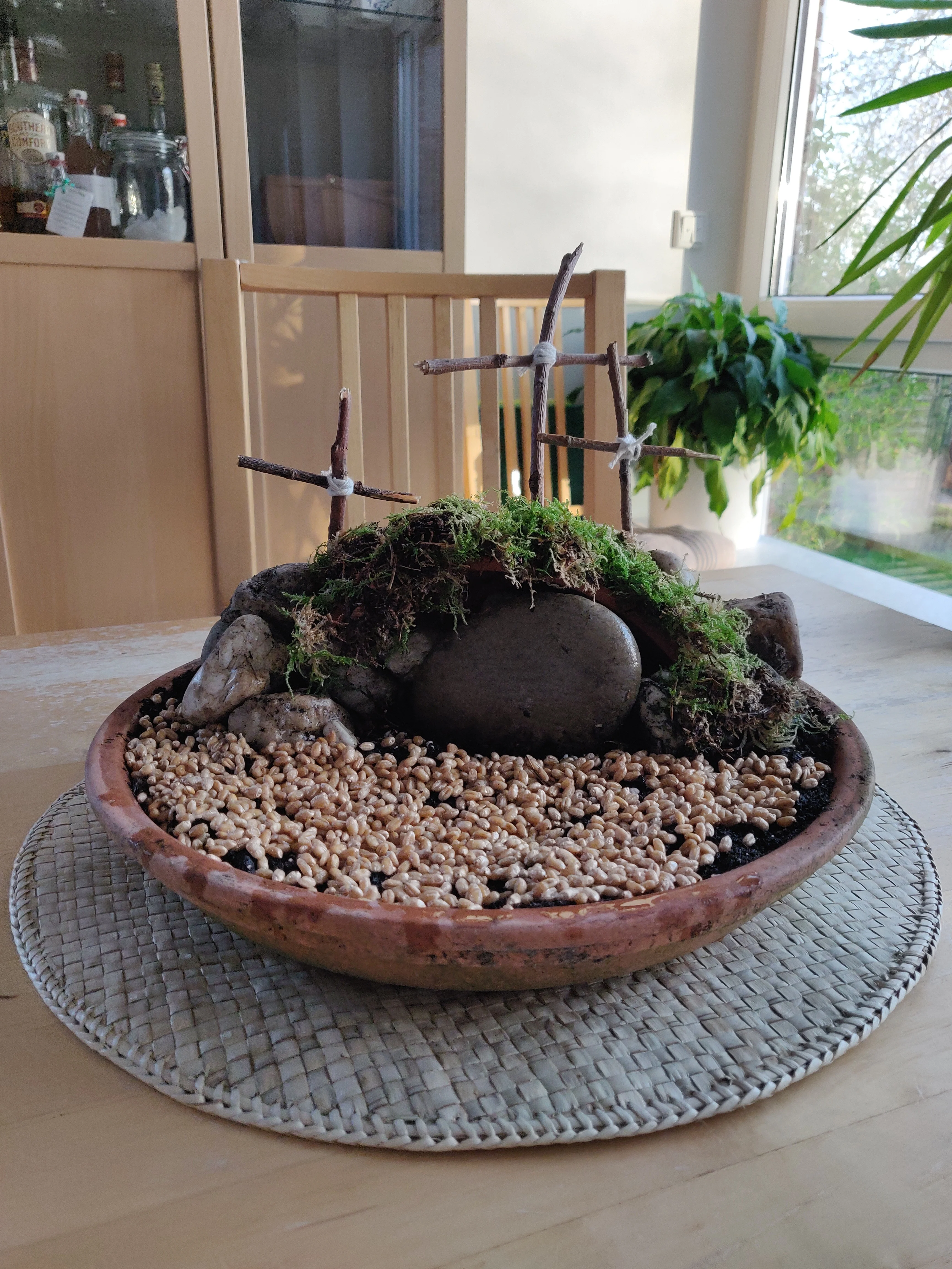 Ostergarten mit Steinhügel, drei Kreuzen und Samenkörnern