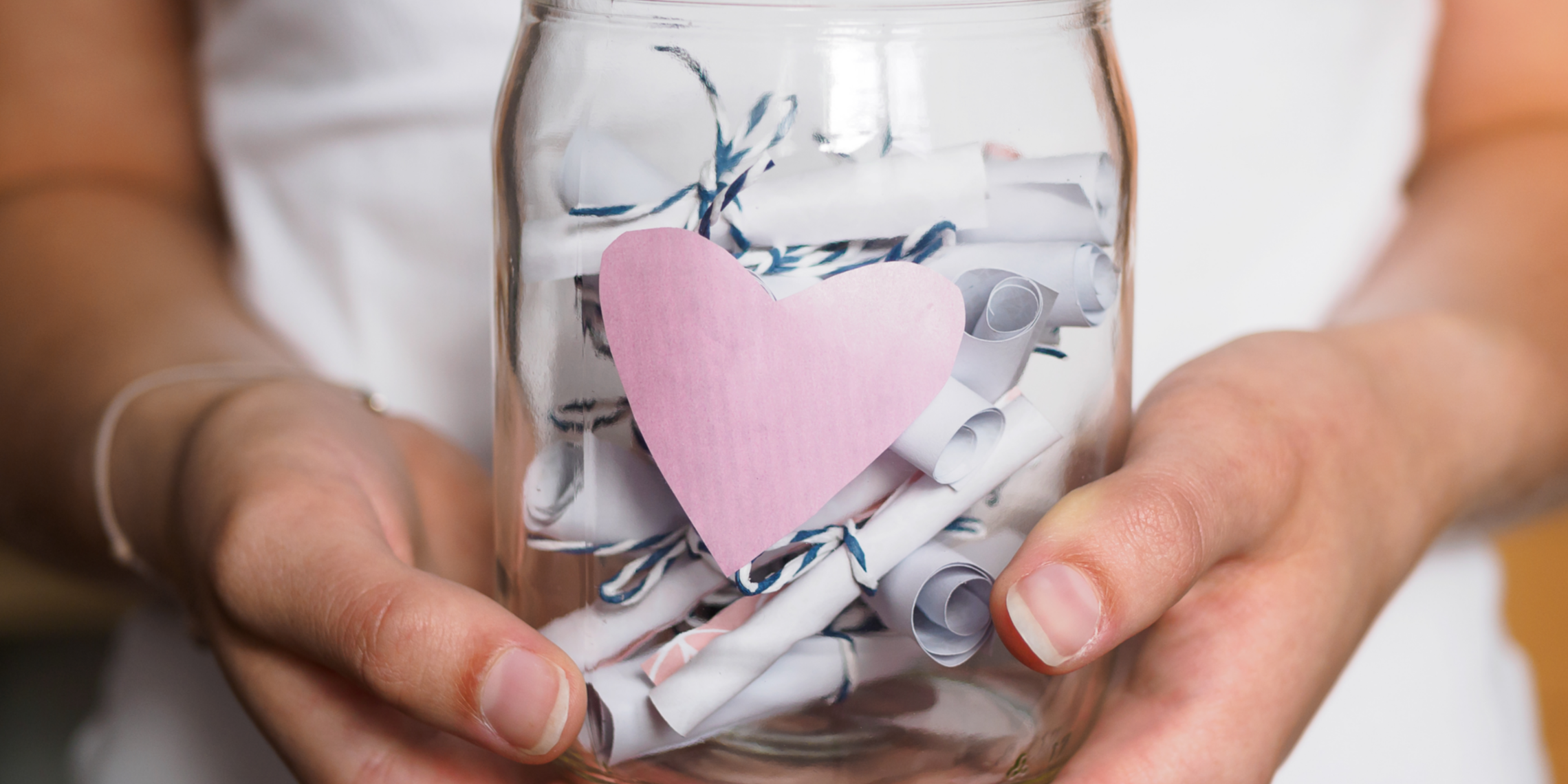 Kind hält Einmachglas mit zetteln in der Hand