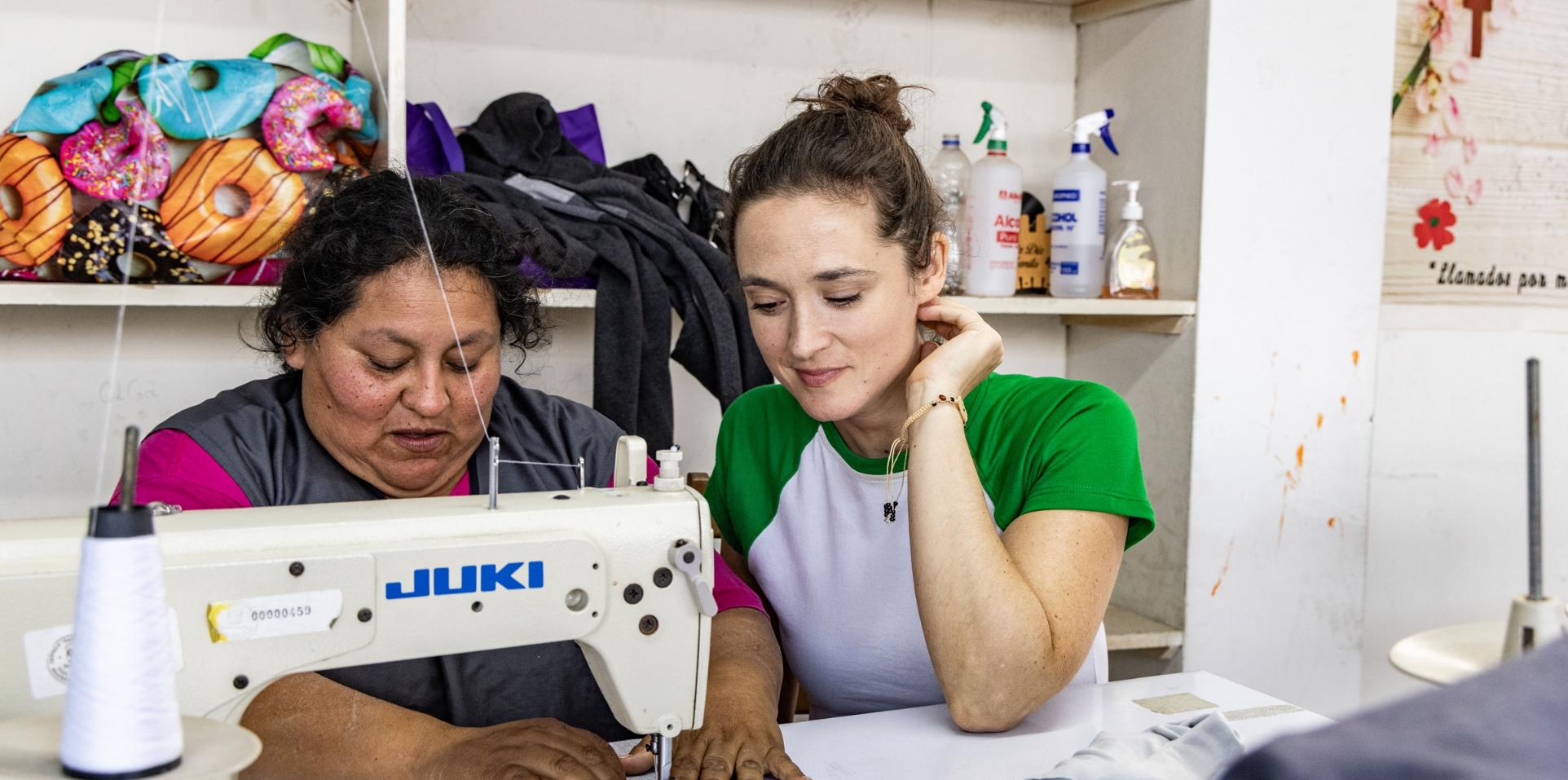 Die Bochumer Schauspielerin Friederike Becht schaut Susana Raquel Guiller Alegría von der Asociación Papico beim Nähen über die Schulter. Nachdem eine Ölpest den Fischern die Lebensgrundlage entzogen hatte, hat Susana mit anderen Frauen die Initiative ergriffen. Die Teilnehmerinnen ihrer Nähkurse erhalten Zertifikate, sodass sie auch normierte Produkte wie Schulkleidung anbieten und so mehr Geld verdienen können.