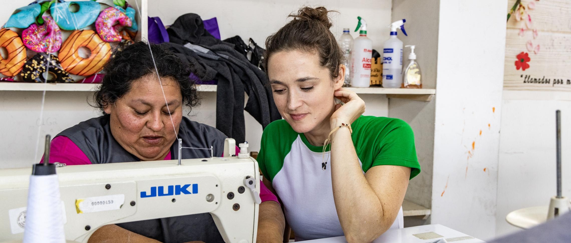 Die Bochumer Schauspielerin Friederike Becht schaut Susana Raquel Guiller Alegría von der Asociación Papico beim Nähen über die Schulter. Nachdem eine Ölpest den Fischern die Lebensgrundlage entzogen hatte, hat Susana mit anderen Frauen die Initiative ergriffen. Die Teilnehmerinnen ihrer Nähkurse erhalten Zertifikate, sodass sie auch normierte Produkte wie Schulkleidung anbieten und so mehr Geld verdienen können.