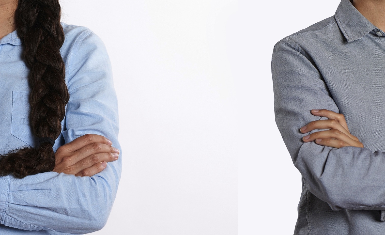 Zwei Menschen stehen mit verschränkten Armen mit größerem Abstand nebeneinander. Man sieht, dass es eine Frau (links) und ein Mann (rechts) ist, aber kein Gesicht.