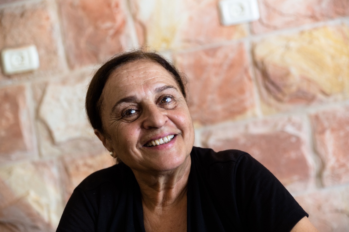 Porträt einer Frau, der palästinensischen Autorin Sumaya Farhat-Naser, vor einer Mauer