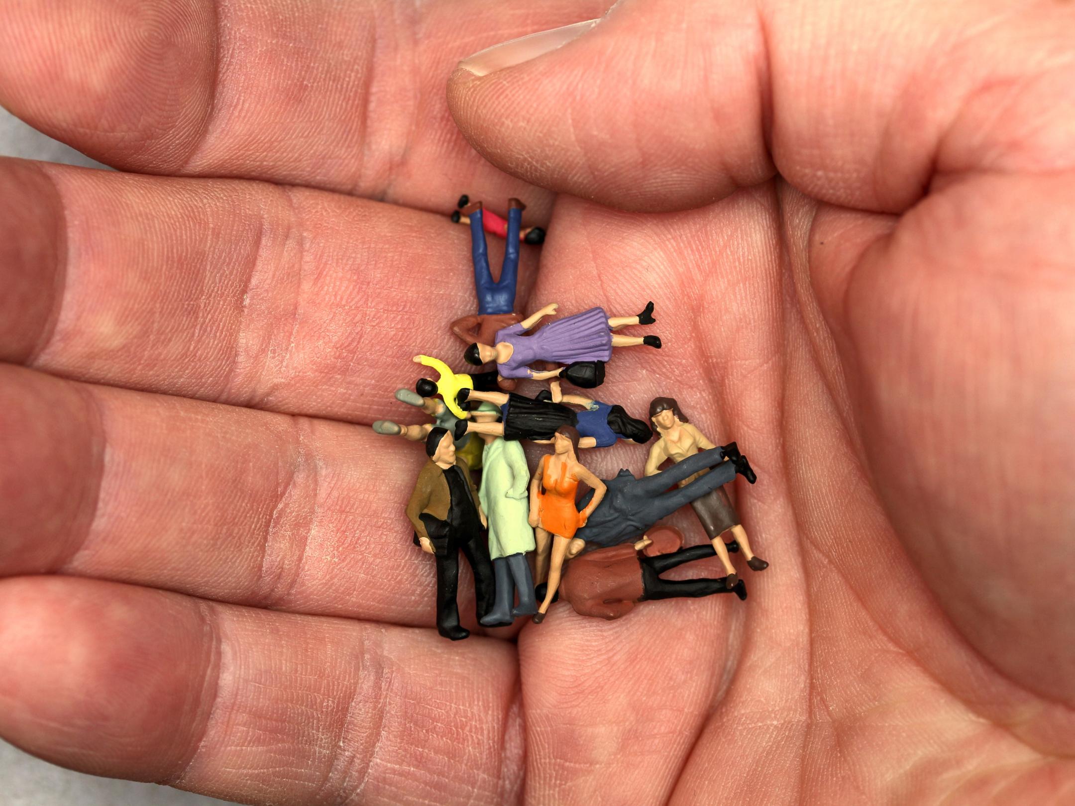 Kleine Spielfiguren (Männer, Frauen, verschiedene Personen) liegen auf einer Handfläche