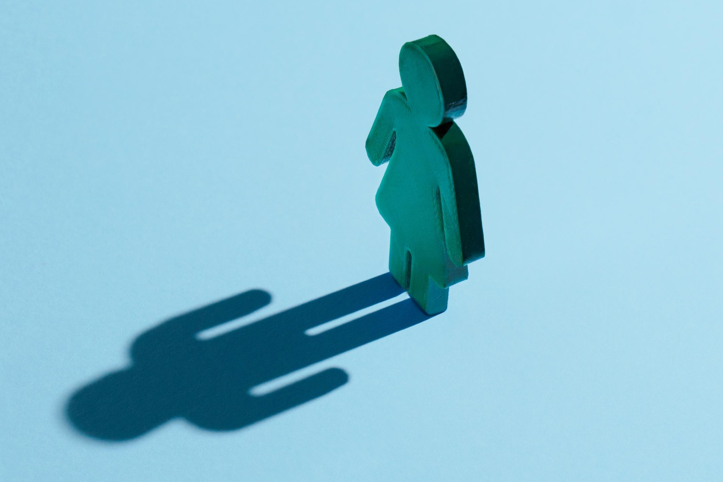 Eine Figur einer Frau, in ihren symbolischen Konturen, die einen Schatten eines Mannes wirft.