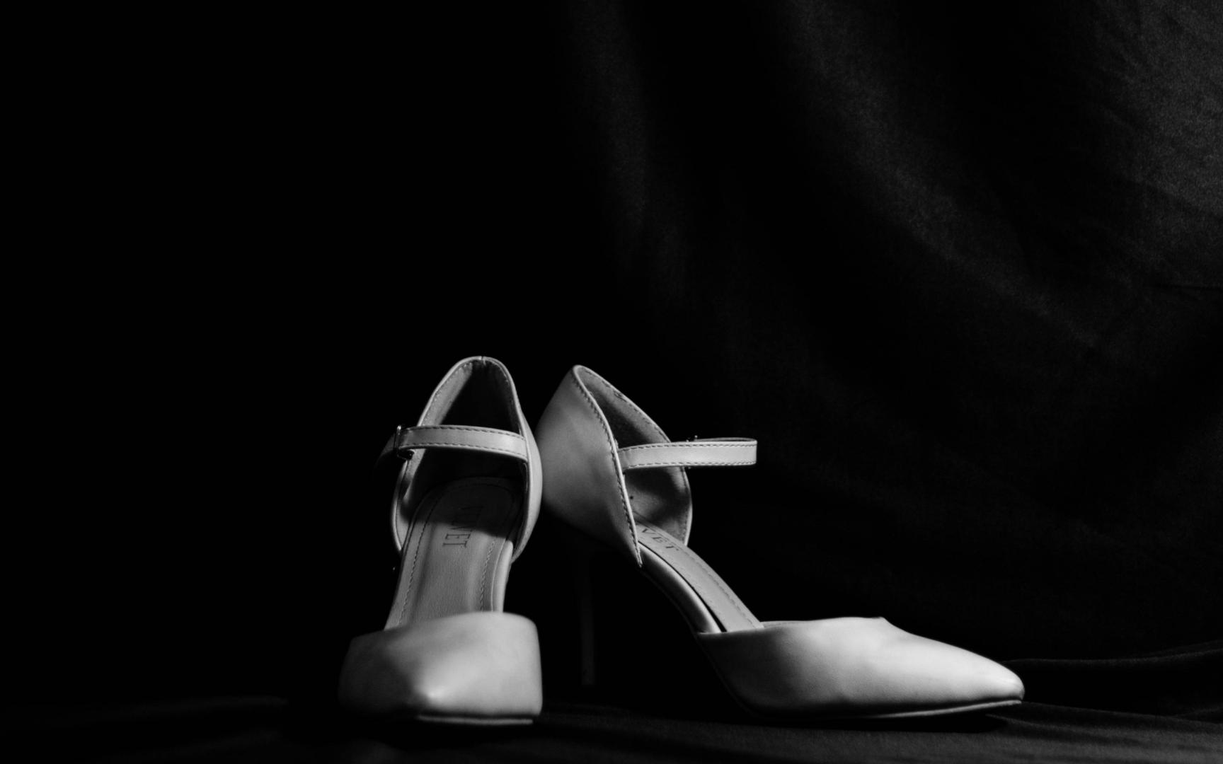 Ein Paar Frauenschuhe, hohe Pumps, vor schwarzem Hintergrund.