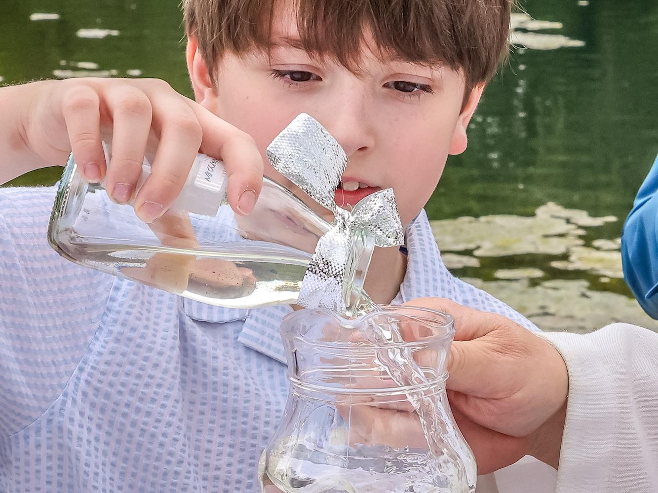 Ferdinand füllt das Wasser, das er morgens aus der Schwalm geschöpft hat, in den Krug. Damit wird der Achtjährige getauft.