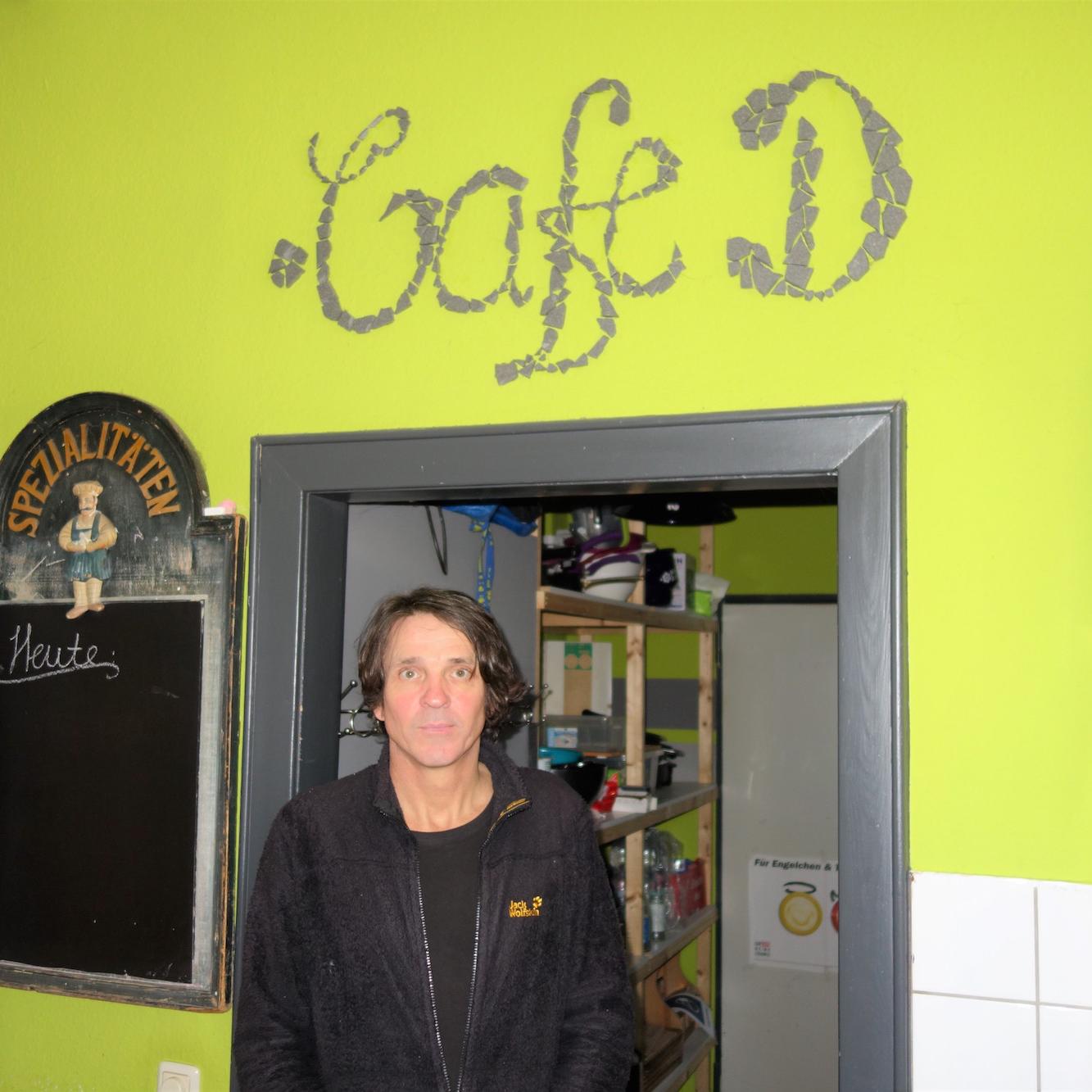 Andreas Schön, der stellvertretende Leiter der Dürener Sucht- und Drogenberatung, vor dem Namen des Cafés im Innern.