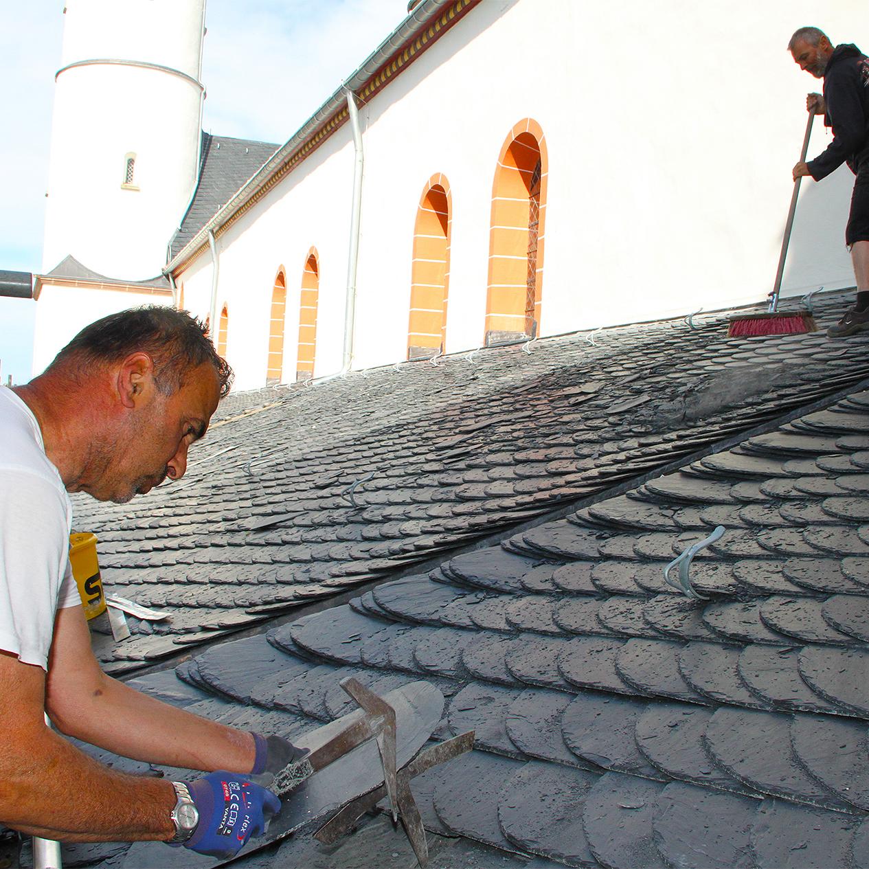 Gemäß „Altdeutscher Deckung“ ein Dach zu beschiefern, das kann nicht jeder Dachdecker. Geselle Ergin Birihci (vorne) weiß, wie es geht. Gesellenkollege Heinz Beyer fegt das Dach.