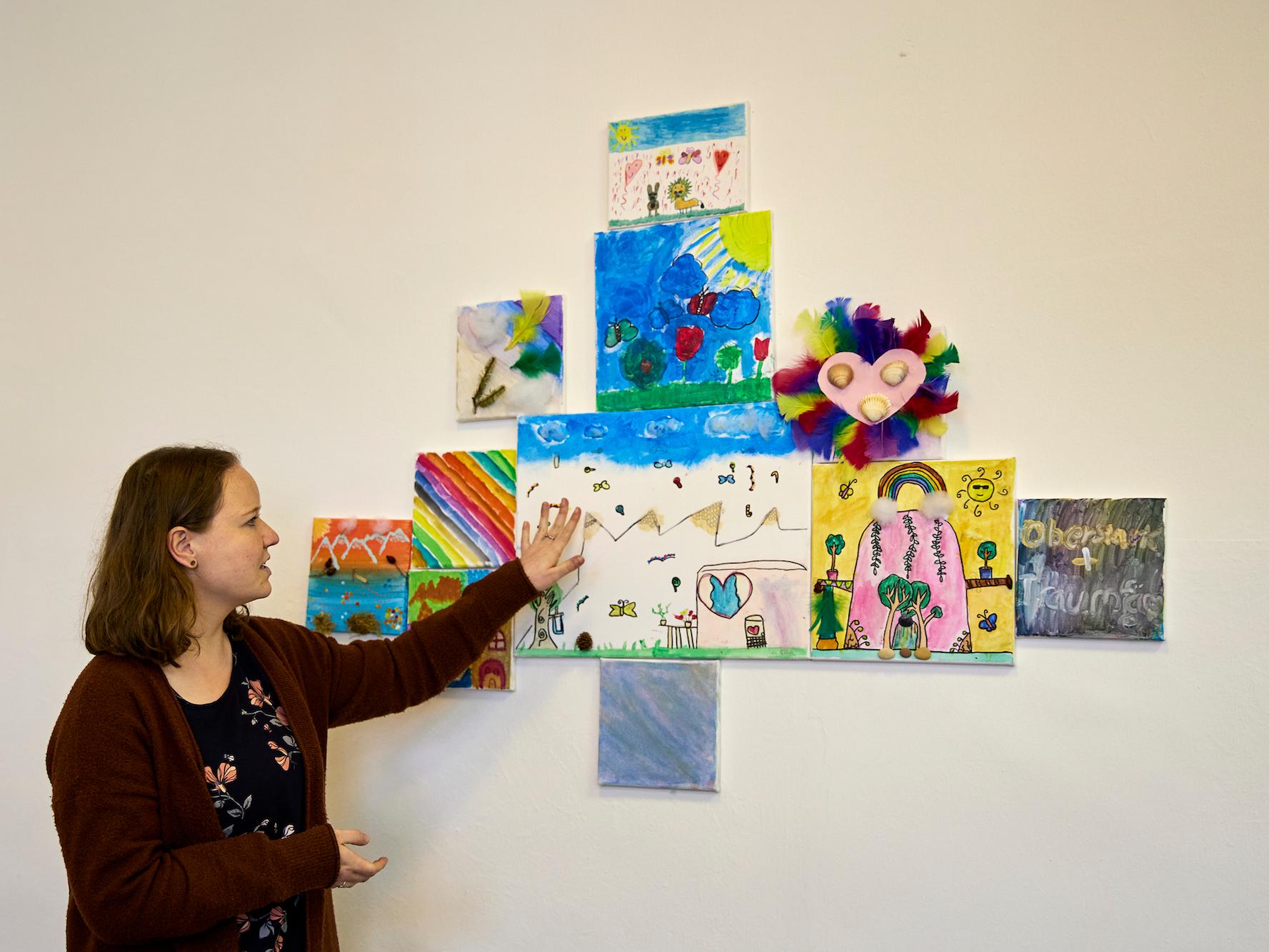 Ellen Sachsenmaier zeigt die Ergebnisse eines kunsttherapeutischen Angebots, bei dem die Kinder einen sicheren Ort malen sollten. An diesen Ort können sie sich gedanklich zurückziehen, wenn sie Stress oder Angst haben.