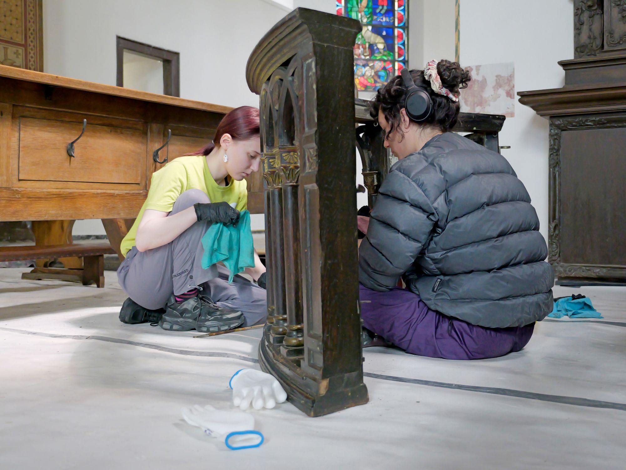 Mit Feingefühl: Elianne (li.) und Elena entfernen den Schlamm von einer alten Kirchenbank.