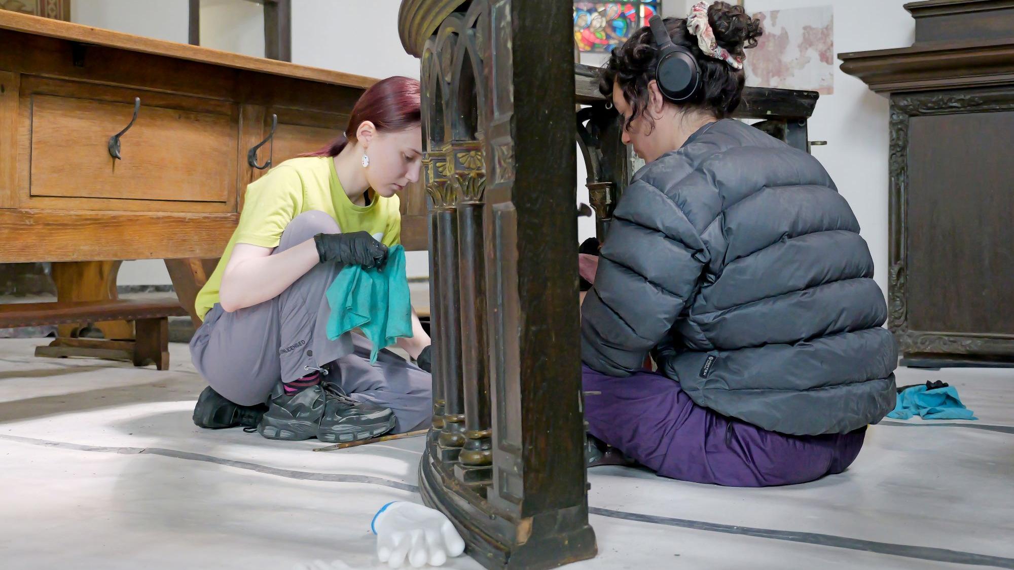 Mit Feingefühl: Elianne (li.) und Elena entfernen den Schlamm von einer alten Kirchenbank.