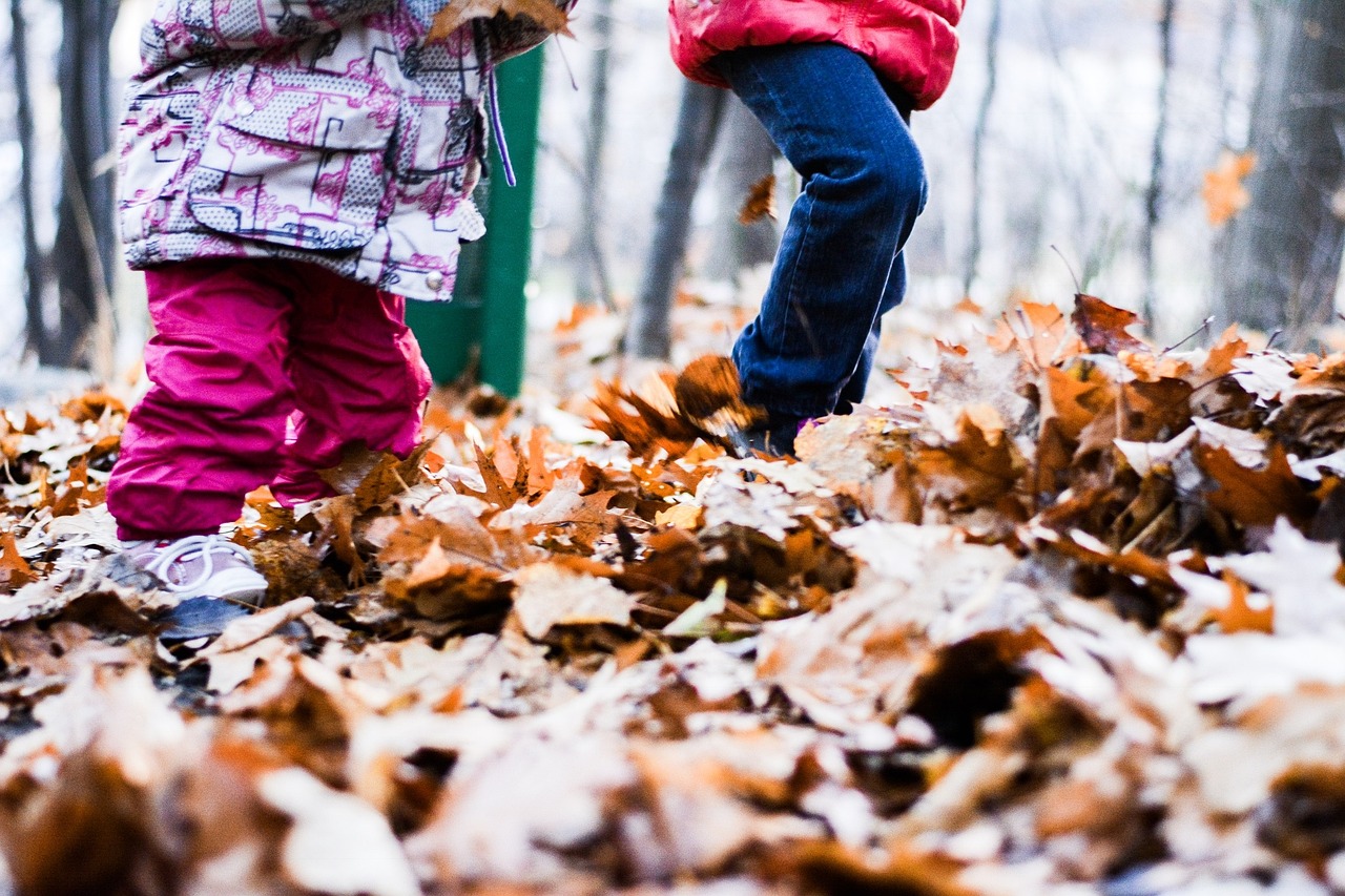 Kinder auf Herbstblätters am Boden